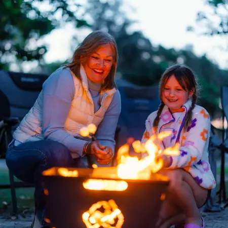 A grandmother and granddaughter are enjoying a campfire